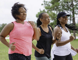 Three women speed-walk outdoors.