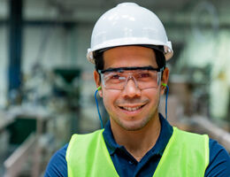 A man wearing a high-vis vest, hardhat, goggles and earplugs.