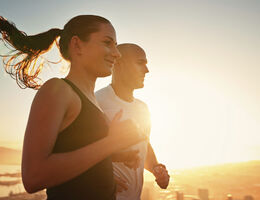 A jogging couple backlit by sun.